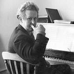 Ron Grainer seated at a piano